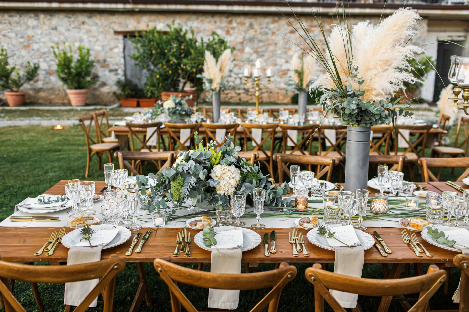 Elegantly set long banquet table at an estate venue — pampas grass arrangements and candlelight